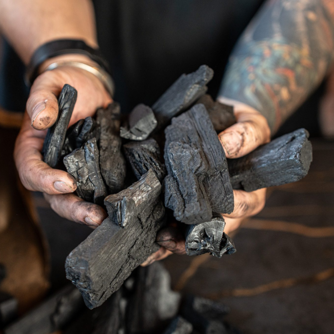 Houtskool in handen van een man